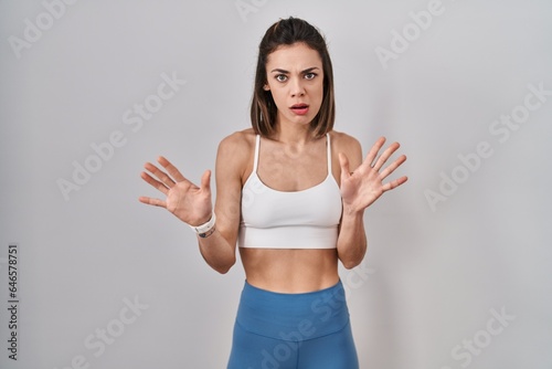 Hispanic woman wearing sportswear over isolated background moving away hands palms showing refusal and denial with afraid and disgusting expression. stop and forbidden.