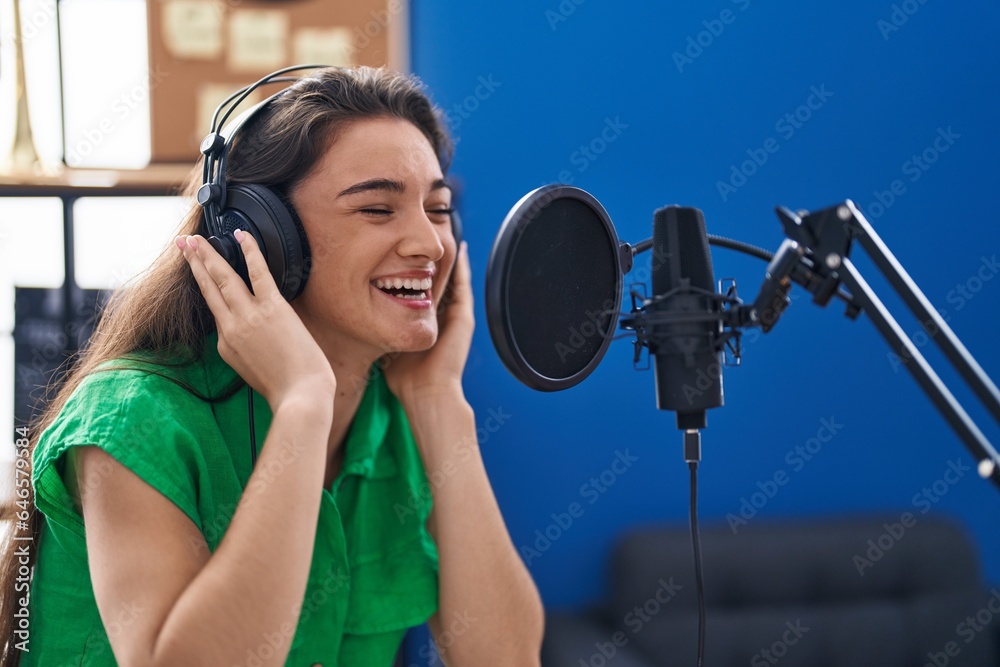 Young hispanic woman artist singing song at music studio