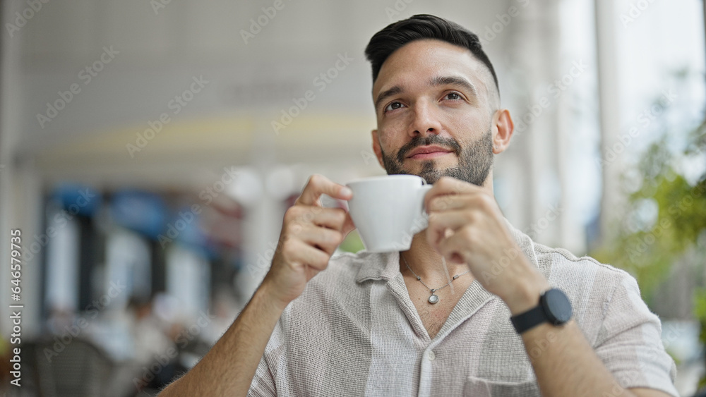 Young hispanic man holding cup of coffee at coffee shop terrace Young hispanic man holding cup of coffee at coffee shop terrace