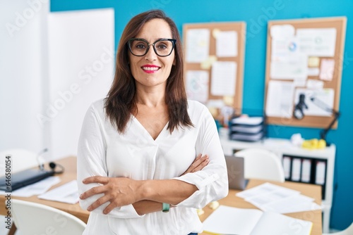 Young beautiful hispanic woman business worker smiling confident standing with arms crossed gesture at office