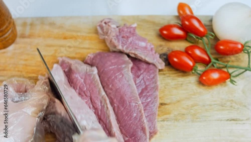 butcher cuts a large piece of selected meat on a steel table photo