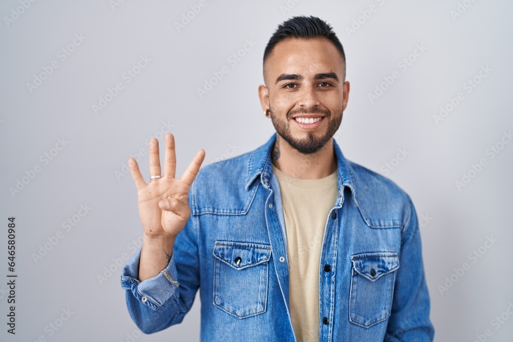 Young hispanic man standing over isolated background showing and pointing up with fingers number four while smiling confident and happy. Young hispanic man standing over isolated background showing and pointing up with fingers number four while smiling confident and happy.