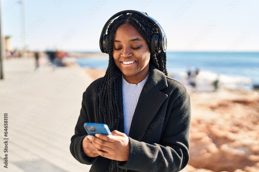 African american woman smiling confident listening to music at seaside