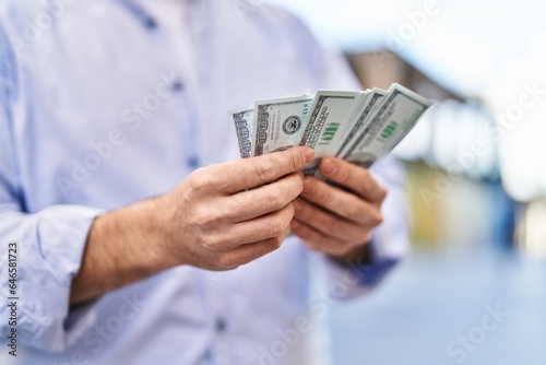 Young caucasian man counting dollars at street