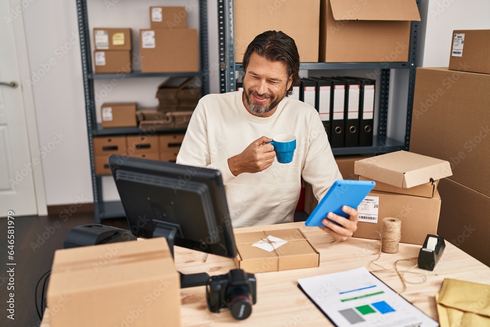 Middle age man ecommerce business worker using touchpad drinking coffee at office Middle age man ecommerce business worker using touchpad drinking coffee at office