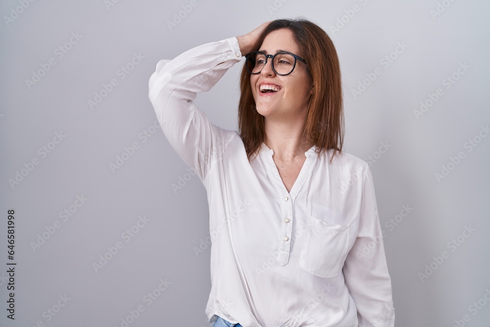 Brunette woman standing over white isolated background smiling confident touching hair with hand up gesture, posing attractive and fashionable Brunette woman standing over white isolated background smiling confident touching hair with hand up gesture, posing attractive and fashionable