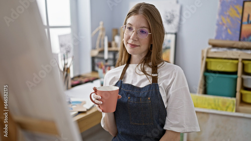 Young blonde woman artist looking draw drinking coffee at art studio