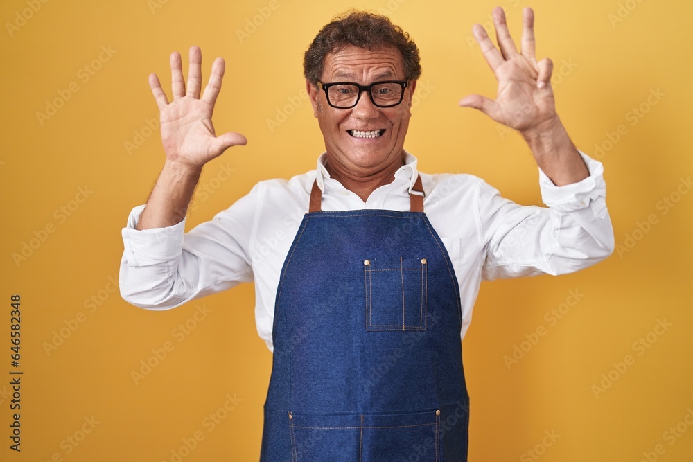 Middle age hispanic man wearing professional cook apron showing and pointing up with fingers number nine while smiling confident and happy. Middle age hispanic man wearing professional cook apron showing and pointing up with fingers number nine while smiling confident and happy.
