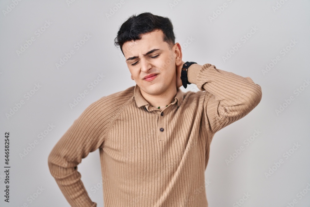 Non binary person standing over isolated background suffering of neck ache injury, touching neck with hand, muscular pain Non binary person standing over isolated background suffering of neck ache injury, touching neck with hand, muscular pain