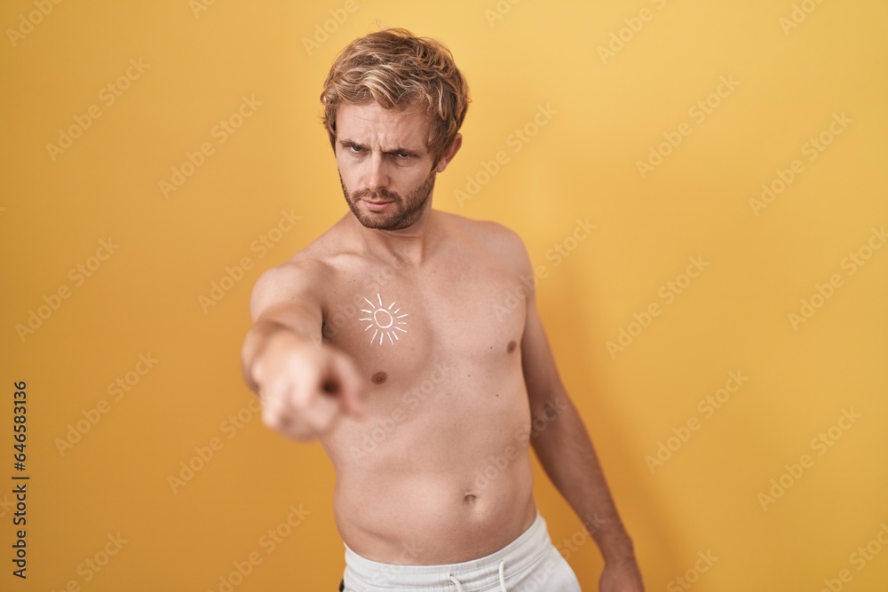 Caucasian man standing shirtless wearing sun screen pointing displeased and frustrated to the camera, angry and furious with you