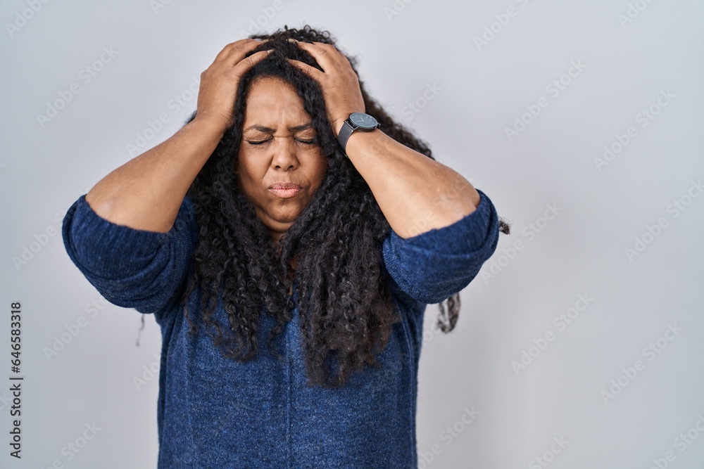 Plus size hispanic woman standing over white background suffering from headache desperate and stressed because pain and migraine. hands on head. Plus size hispanic woman standing over white background suffering from headache desperate and stressed because pain and migraine. hands on head.