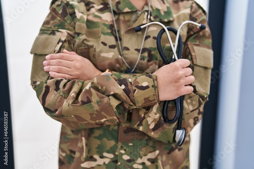 Young hispanic woman army doctor holding stethoscope at home photo