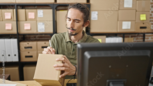 Young hispanic man ecommerce business worker writing on package at office © Krakenimages.com