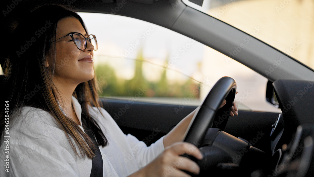 Young beautiful hispanic woman driving a car smiling wearing glasses on the road Young beautiful hispanic woman driving a car smiling wearing glasses on the road