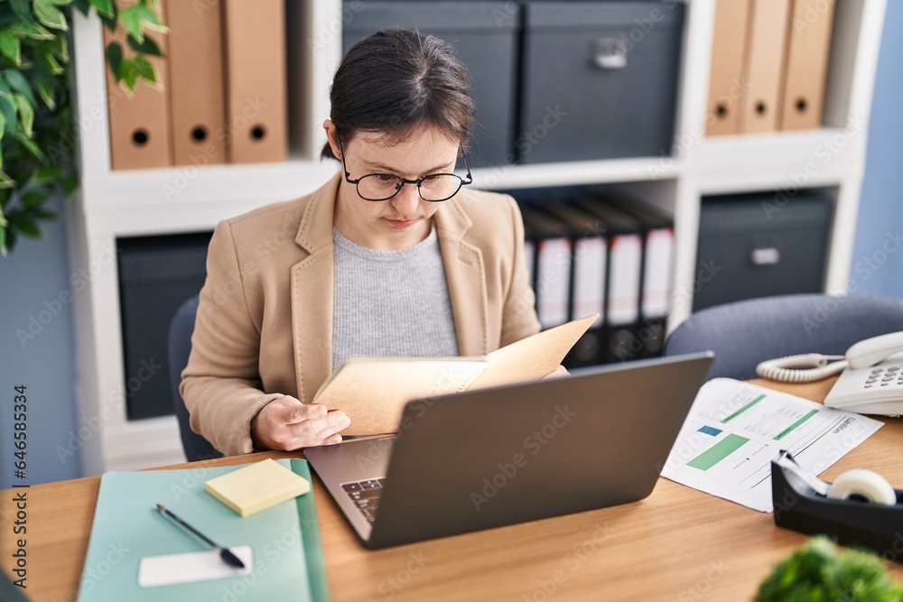 Young woman with down syndrome business worker reading notebook working at office Young woman with down syndrome business worker reading notebook working at office