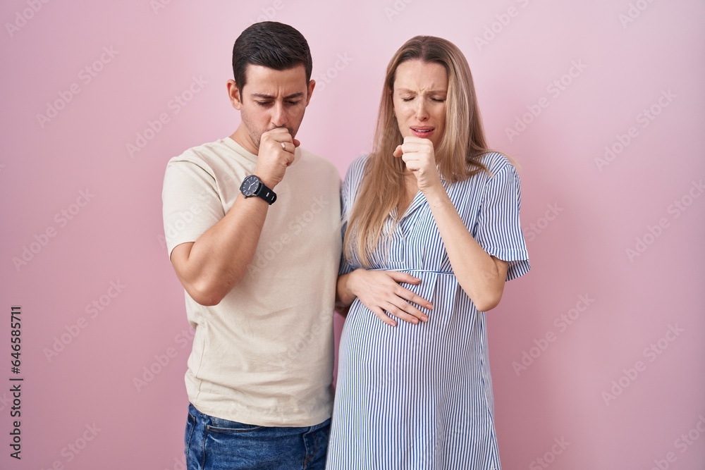 Young couple expecting a baby standing over pink background feeling unwell and coughing as symptom for cold or bronchitis. health care concept. Young couple expecting a baby standing over pink background feeling unwell and coughing as symptom for cold or bronchitis. health care concept.