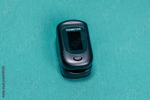 Digital pulse oximeter photographed on a green surgical drape.