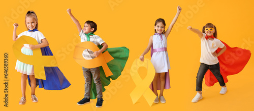 Little girl wearing superhero costume and with golden ribbon on color background. Childhood cancer awareness concept