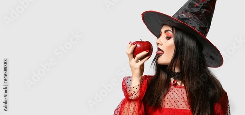 Sexy young witch with poisoned apple on light background with space for text