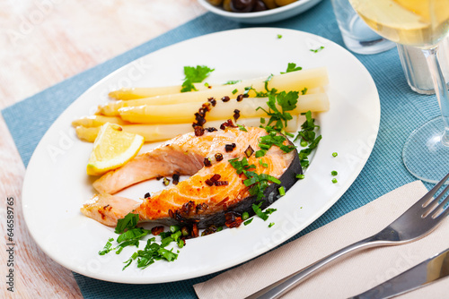 Traditional spanish food, grilled salmon with asparagus served with lemon and greens
