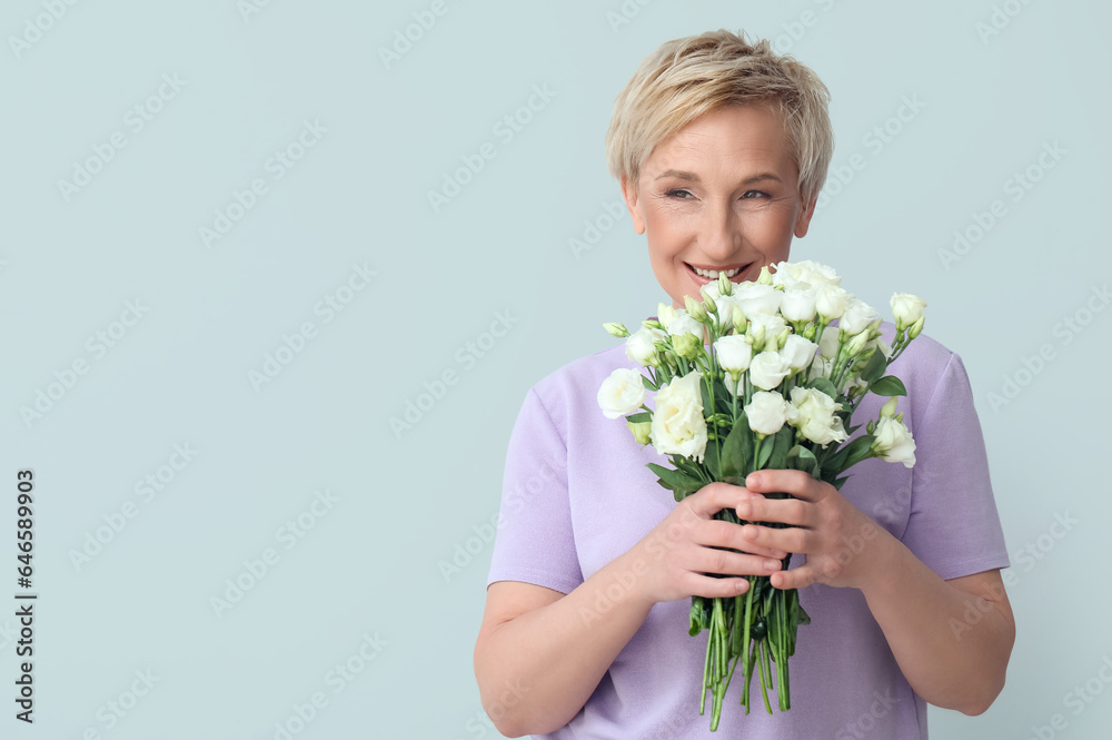 Mature woman with beautiful roses on light background