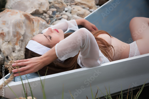 Sexy young woman lying nude in a vintage boat.