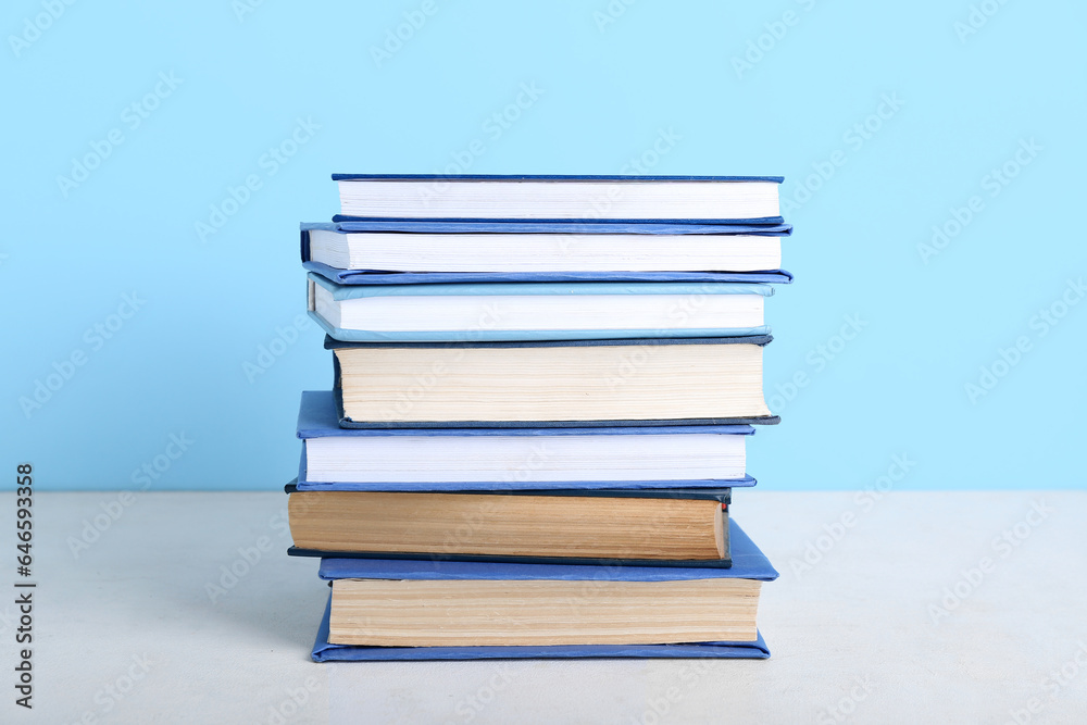 Stack of books on table against blue background Stack of books on table against blue background