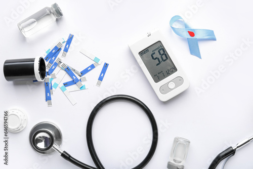 Glucometer, stethoscope, scarificators and blue ribbon on white background. Diabetes concept