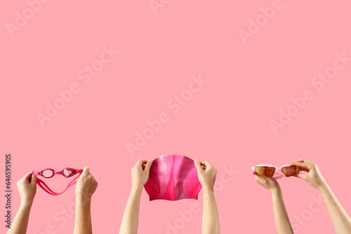 Female hands holding swimming equipment on pink background