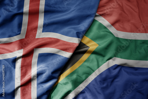 big waving national colorful flag of icelandic and national flag of south africa .