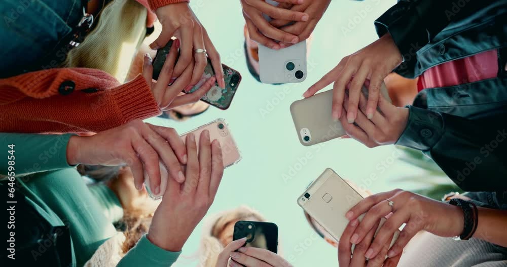 Friends group, circle and phone in low angle, campus or mobile connection with scroll, typing or click in summer. Girl students, smartphone and huddle for social network at high school in Los Angeles