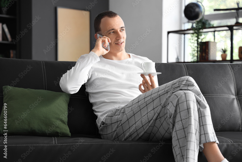 Young man with cup of coffee talking by mobile phone at home Young man with cup of coffee talking by mobile phone at home