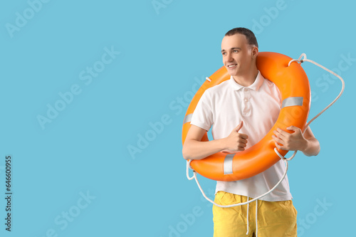 Young man with ring buoy on blue background