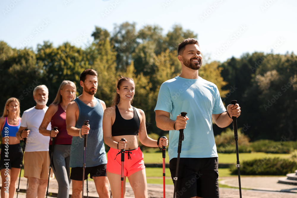 Obraz premium Group of people practicing Nordic walking with poles in park on sunny day