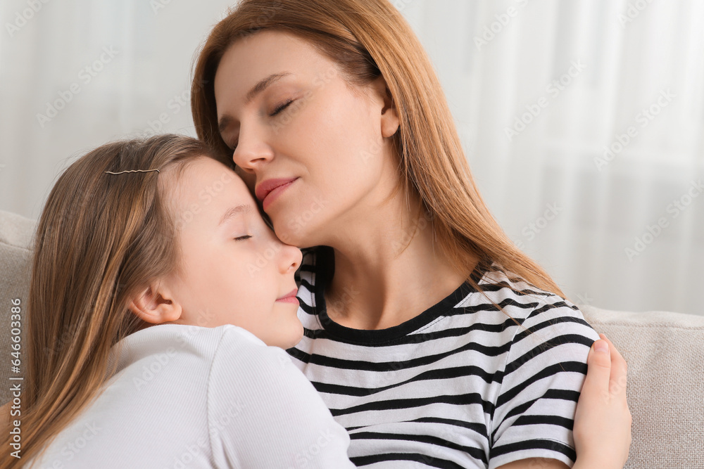 Mother hugging her cute daughter on sofa at home Mother hugging her cute daughter on sofa at home