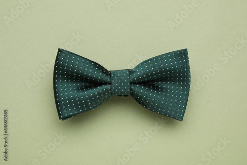 Stylish bow tie with polka dot pattern on pale green background, top view