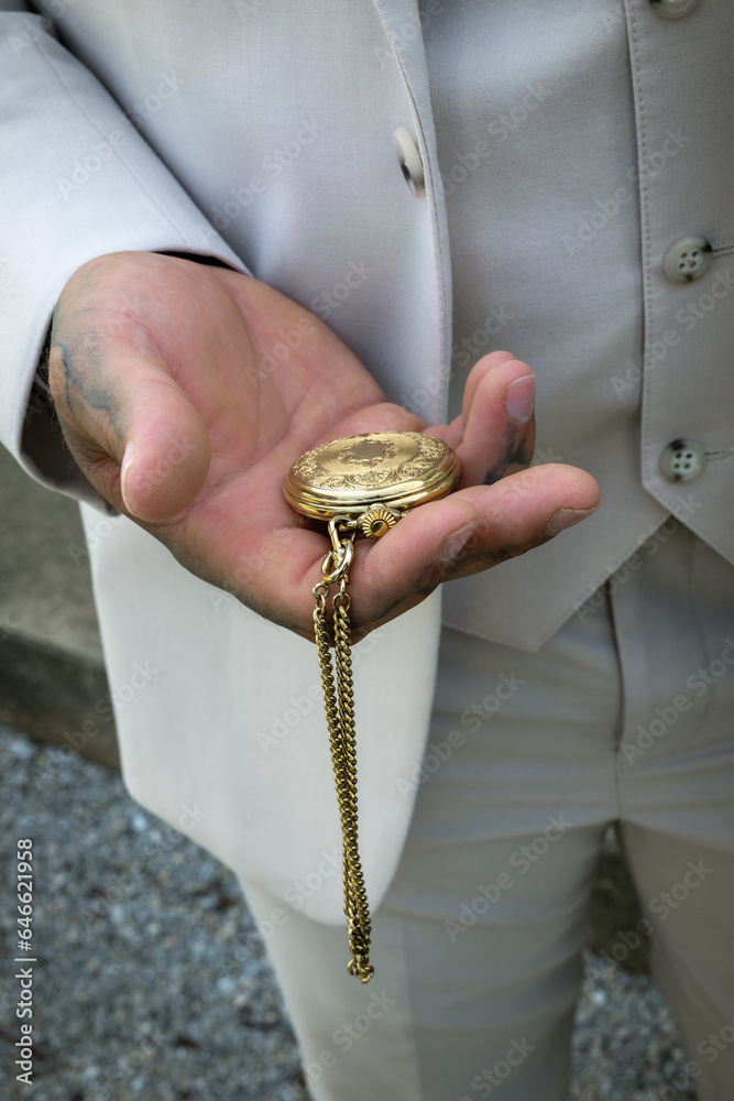 Fototapeta premium man holding gold pocket watch in beige suit