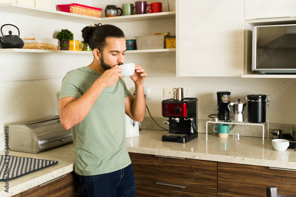 Attractive man enjoying drinking coffee relaxing in the kitchen Attractive man enjoying drinking coffee relaxing in the kitchen
