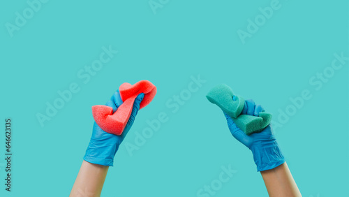 Household hygiene. Cleaning advertising. Home washing sponges tools in janitor hands in rubber gloves isolated on green background empty space.