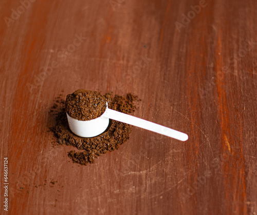 Cuchara llena de café molido sobre una mesa de madera  photo