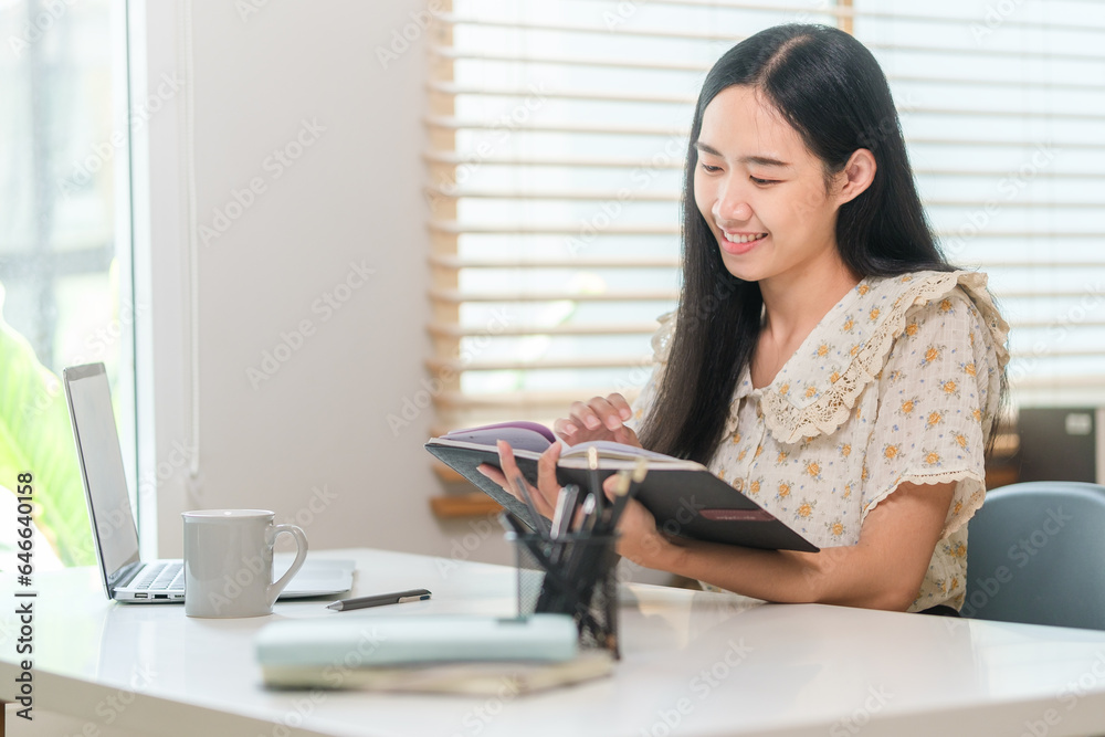 Beautiful young woman using laptop and making notes on notebook. Beautiful young woman using laptop and making notes on notebook.