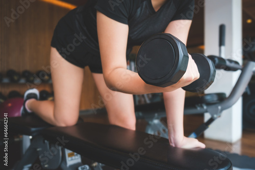 Cropped image of female hands lifting dumbbells at gym. Fitness, workout, gym exercise and healthy lifestyle concept. © wattana