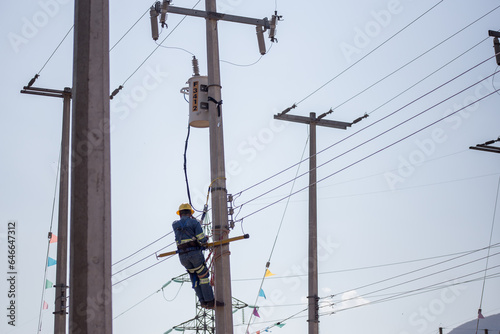 Liniero electricista ingeniero trabajando trepando un poste para reparar y dar mantenimiento a una linea eléctrica y un transformador 
 photo