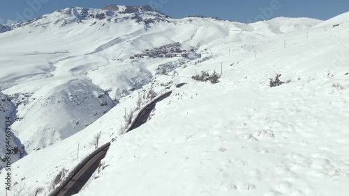 Drone shot of the road on the way to the exclusive ski resort of La Parva filled with snow on a sunny day in the Andes, Chile. photo