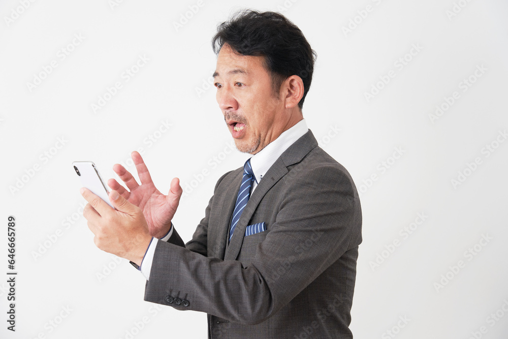スマホを持って驚く中年のビジネスマン　白背景