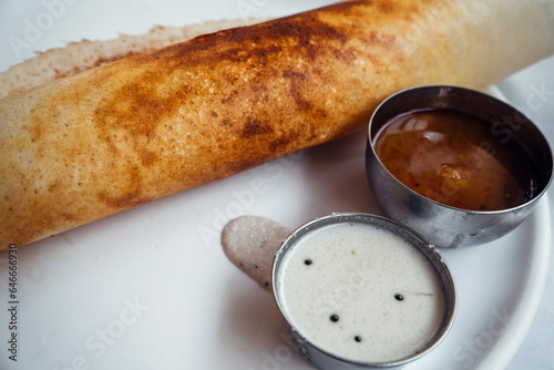 Dosa Ghee roast Dosa, famous south Indian breakfast item which is made in caste iron pan in traditional way and arranged on a white base with side dish ,on a white background photo