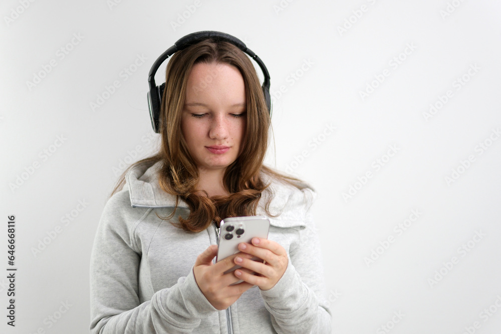 search on the phone for suitable music in playlist teenage girl in headphones chooses a melody to listen wind sportswear on a white background search on the phone for suitable music in playlist teenage girl in headphones chooses a melody to listen wind sportswear on a white background