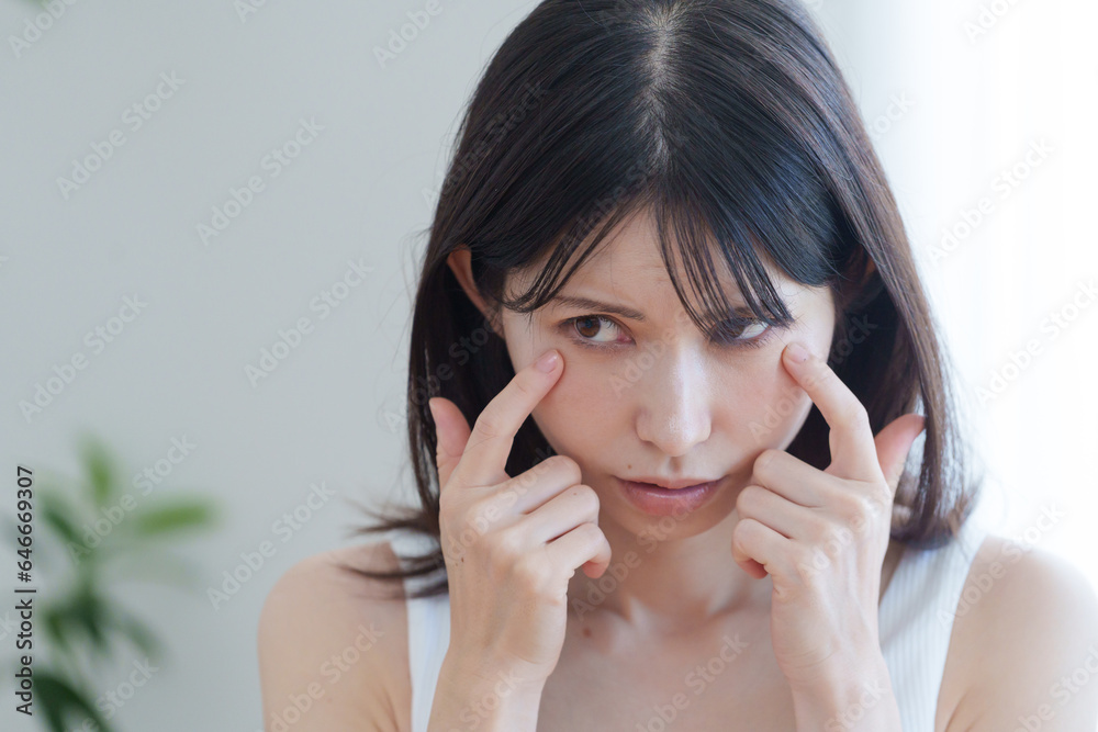 顔の目元に悩む女性 顔の目元に悩む女性