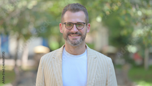 Outdoor Portrait of Smiling Middle Aged Man Looking at Camera