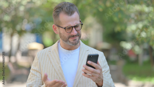 Upset Middle Aged Man get Shocked on Smartphone Outdoor